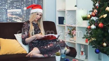 戴着圣诞帽的聪明女人在家坐在沙发上<strong>专心</strong>看书